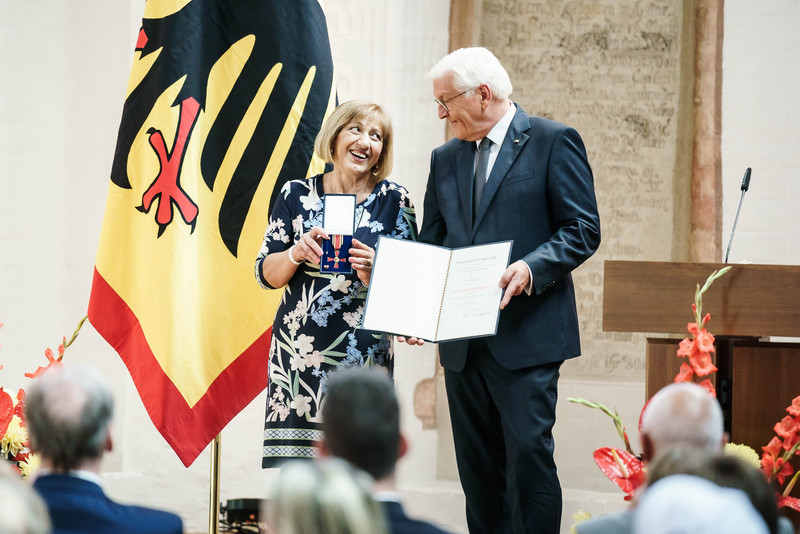 Bundespräsident Frank Walter Steinmeier zeichnet eine Bürgerin mit dem Bundesverdienstorden aus.