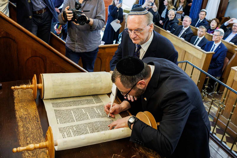 Ministerpräsident Dr. Reiner Haseloff legt seine Hand auf den Schreibenden der Tora-Buchstaben.