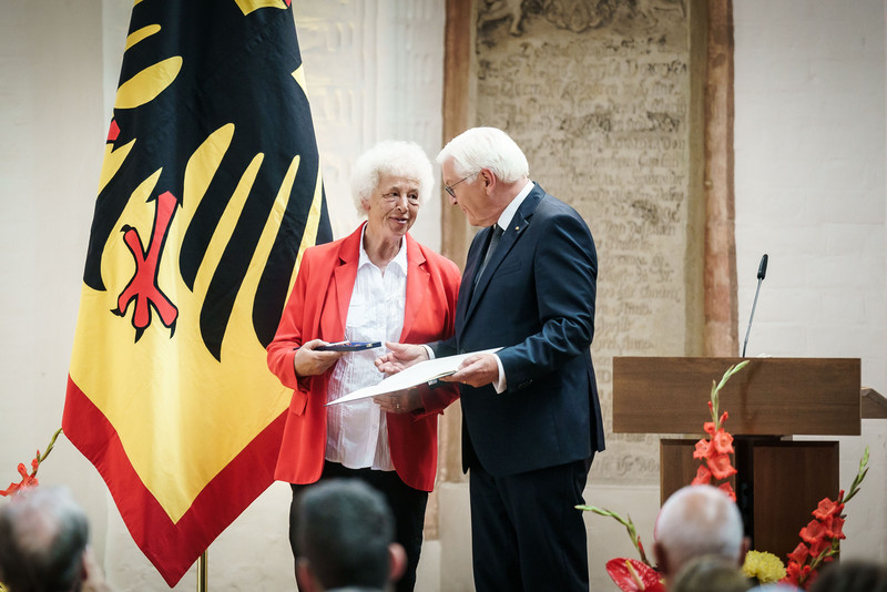 Bundespräsident Frank Walter Steinmeier zeichnet eine Bürgerin mit dem Bundesverdienstorden aus.